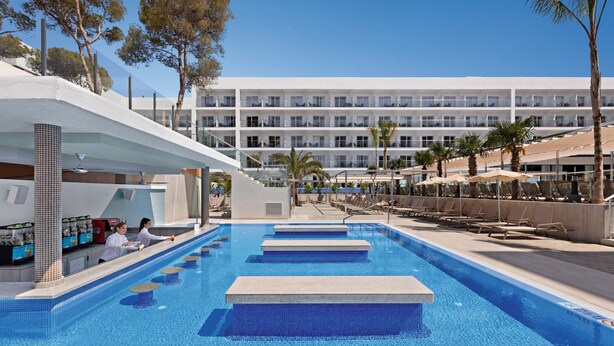 En swimmingpool med flere niveauer og en moderne bygning i baggrunden.