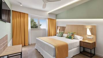 A modern hotel room with a bed, bedside table, lamp, and a ceiling fan.