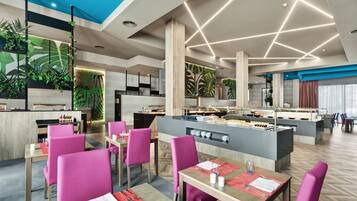 Een modern restaurant met een centraal eiland, heldere plafondlampen en levendige roze stoelen.