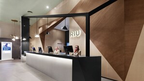En moderne receptionsdisk med et geometrisk vægdesign og et skilt med 'RIU'.