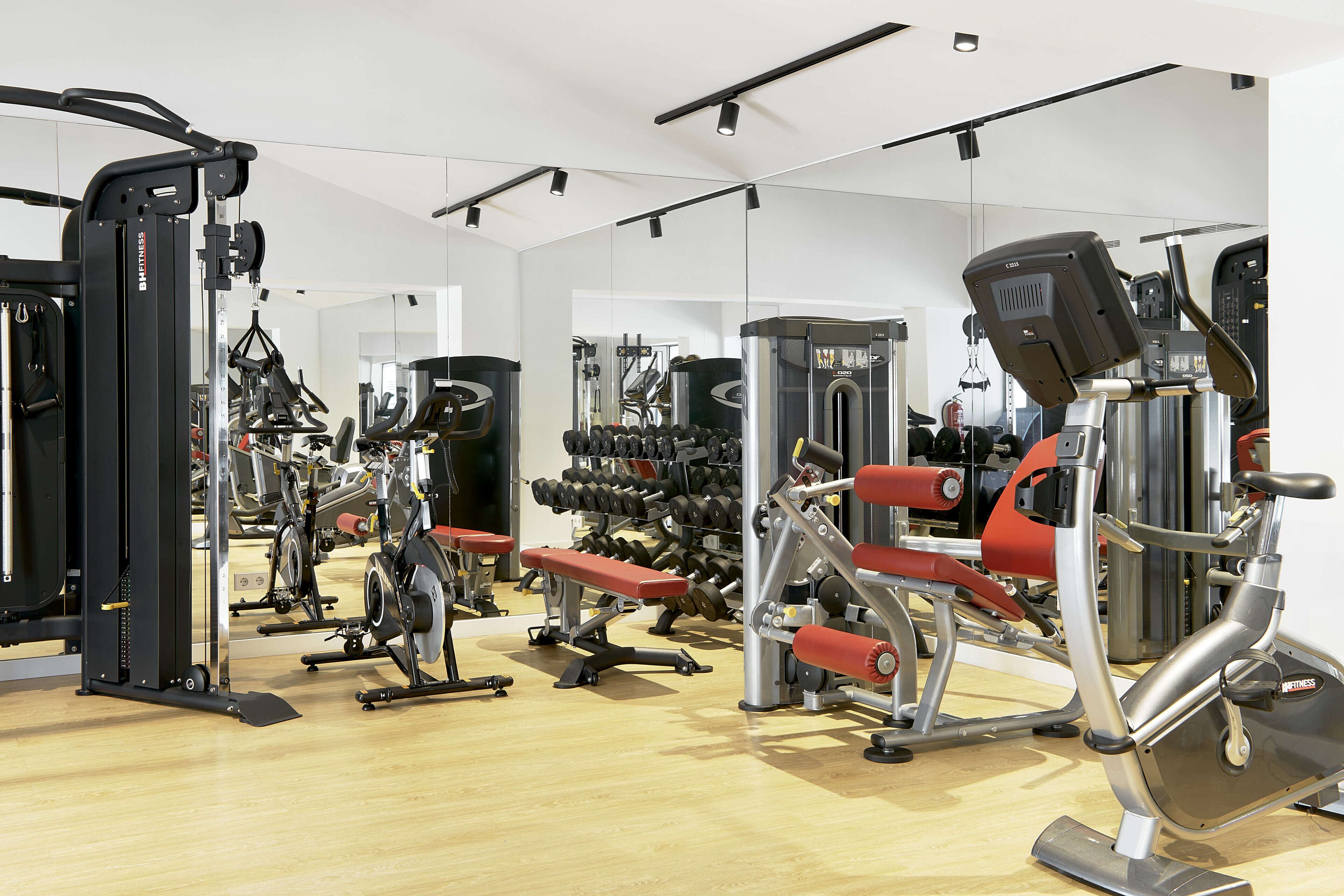A gym with various exercise equipment, including treadmills, weight machines, and free weights.