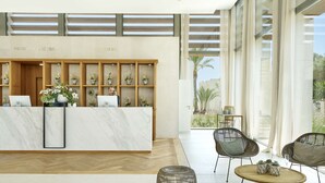 Un espace d’accueil doté d’un comptoir en marbre, d’étagères en bois ornées de plantes et de meubles en osier.