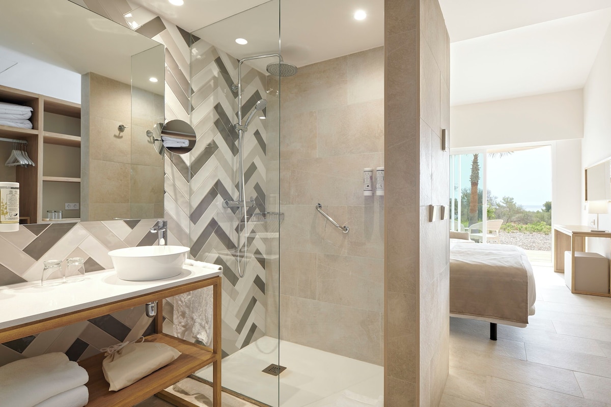 A modern bathroom with a glass-enclosed shower, a white sink, and a large mirror.