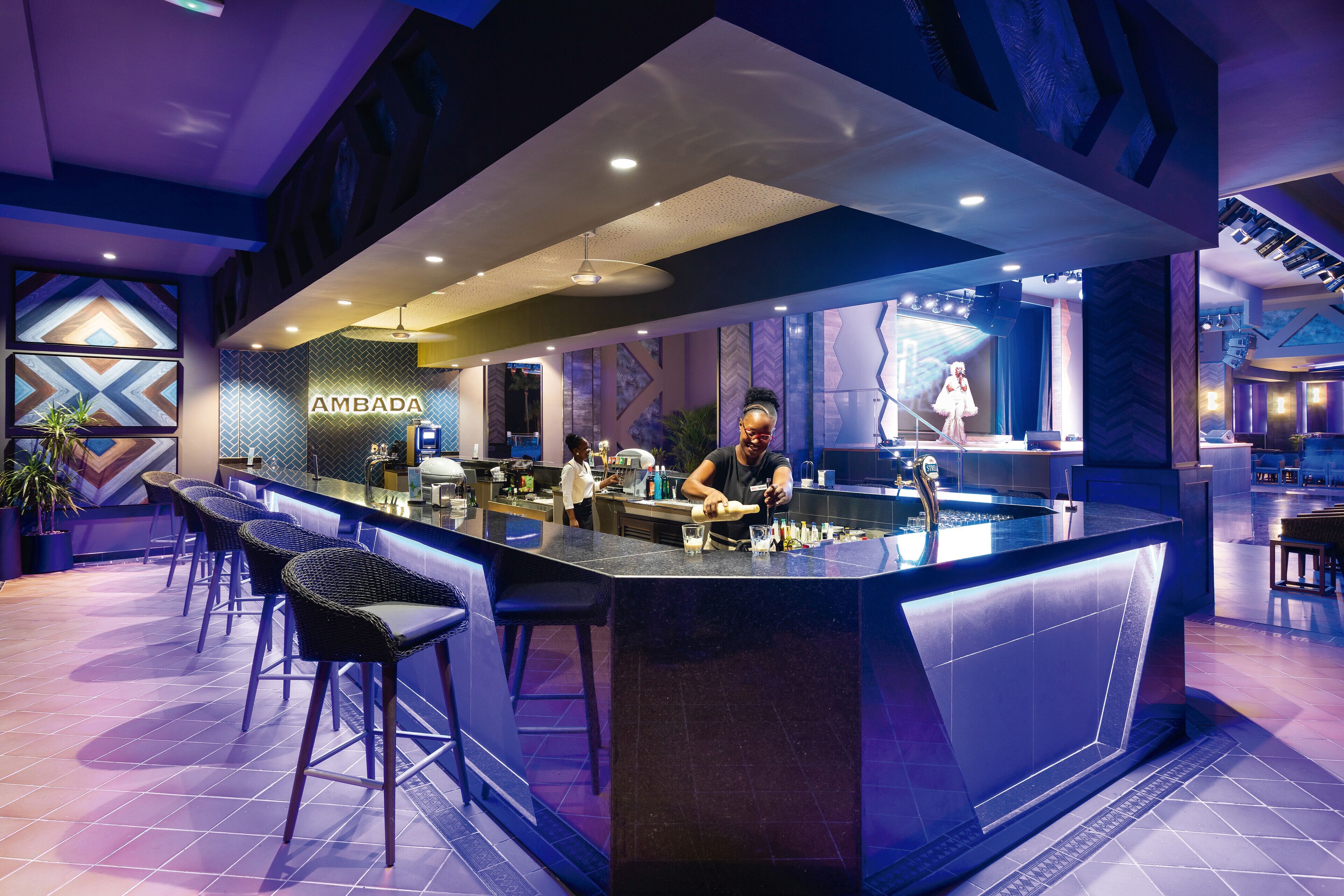 Un área de bar moderna con mostrador, taburetes y un letrero que dice 