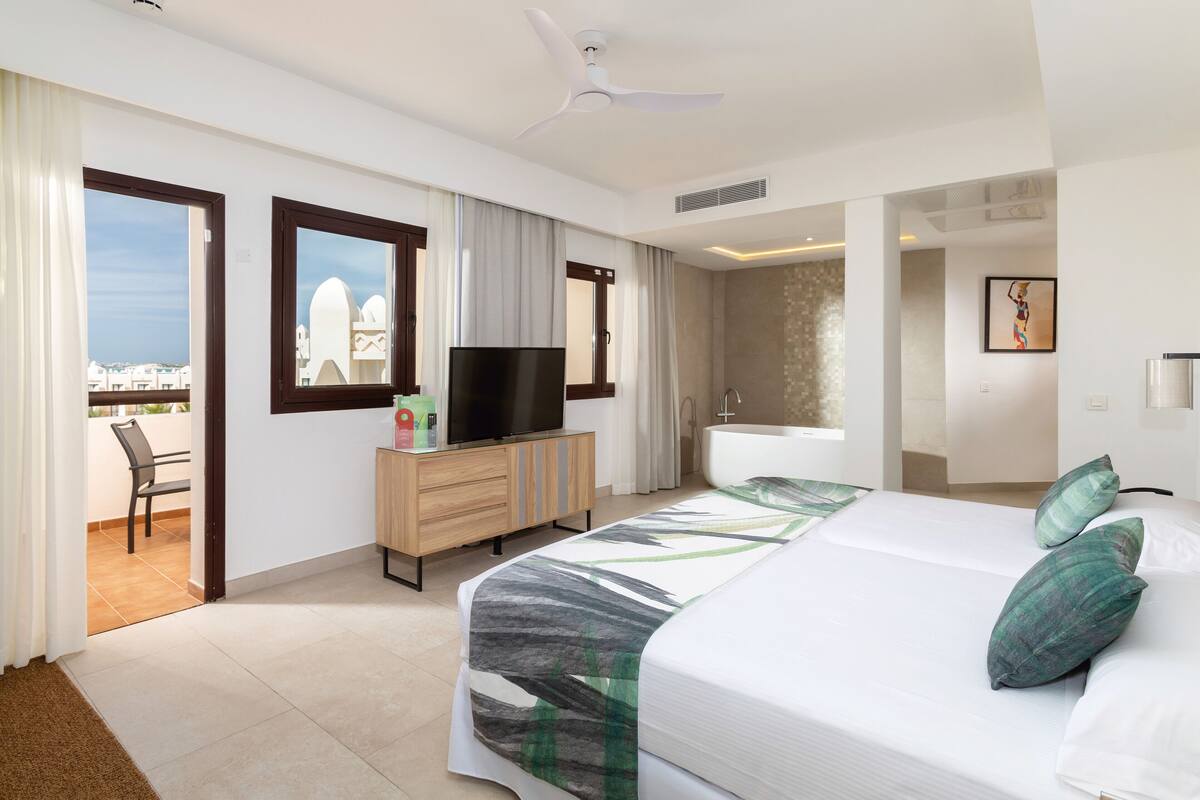 Habitació d'hotel amb llit, televisió, bany i balcó amb vistes.