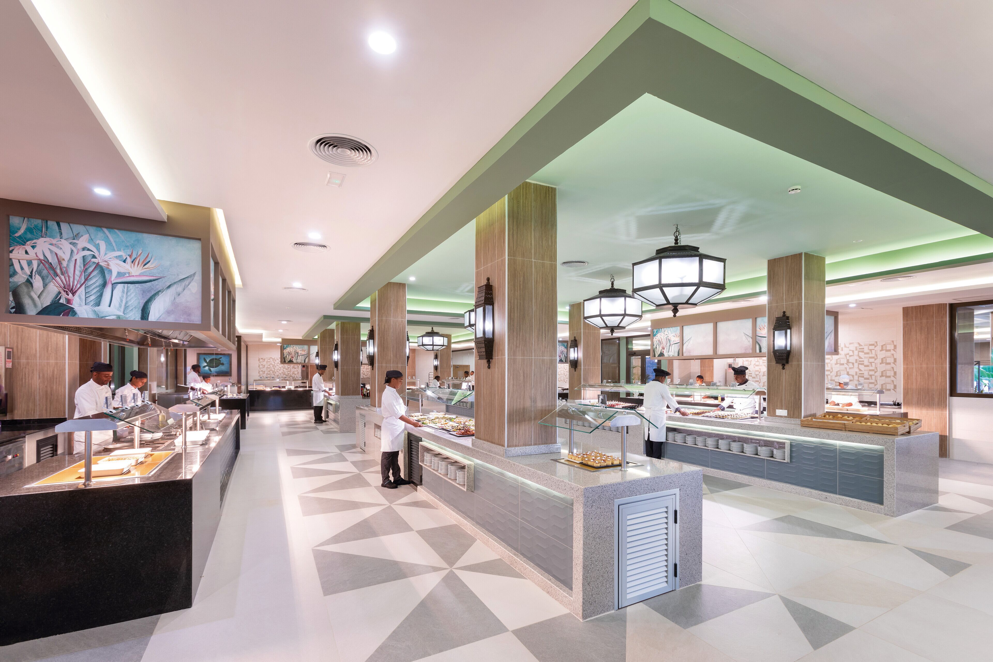 Un hall d’hôtel moderne avec un espace buffet, du personnel au service et un grand tableau accroché au mur.