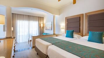 Habitación de hotel con dos camas, un escritorio y un ventanal con cortinas.