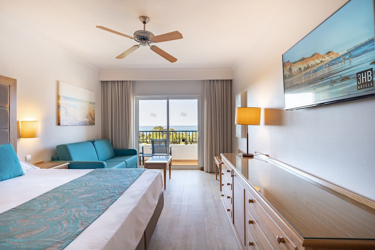 Habitació d'hotel amb llit, sofà, escriptori, televisió i un balcó amb vistes.
