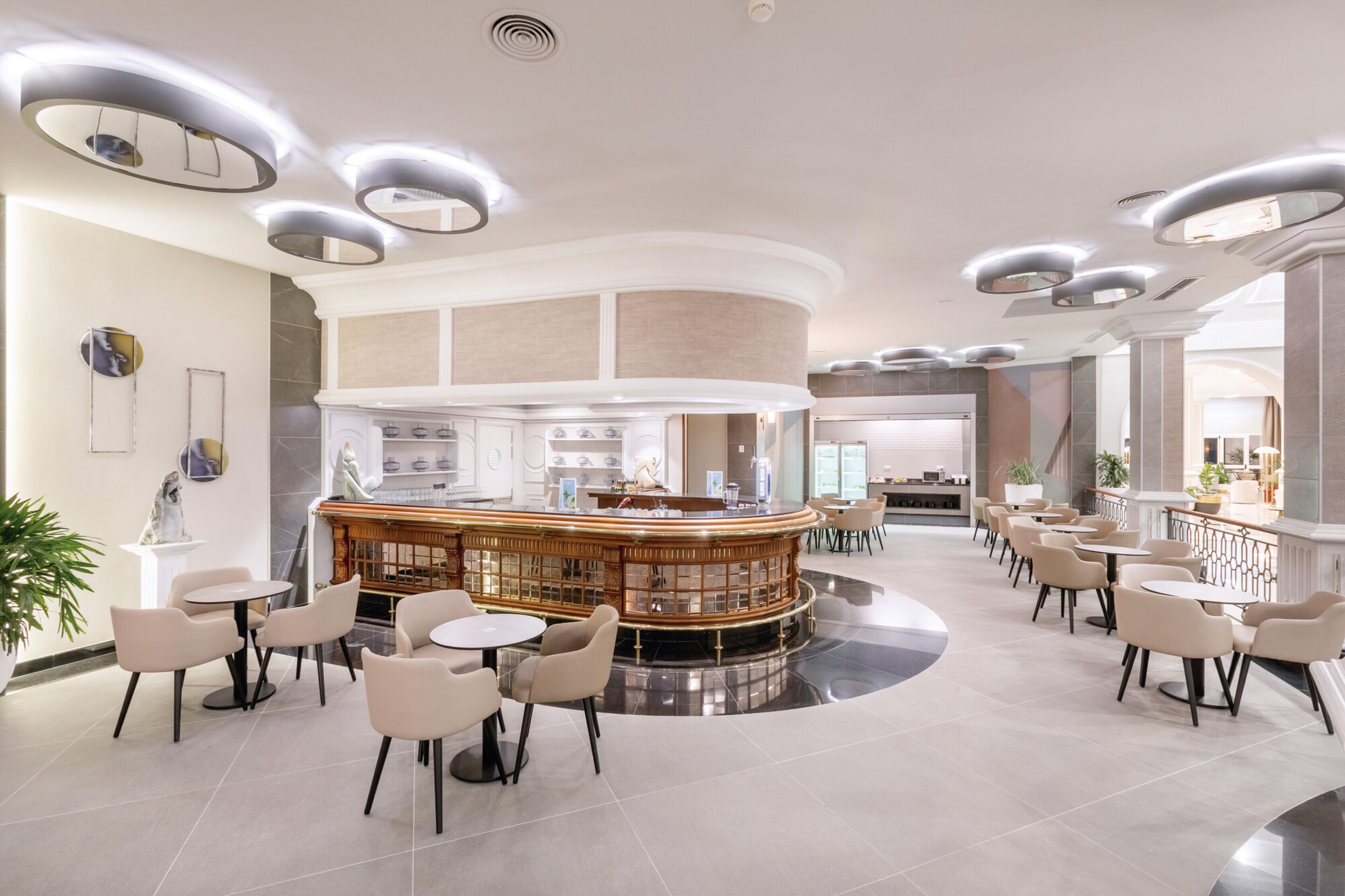 Een moderne hotellobby met een bar in het midden, zitgedeeltes en een receptiebalie.