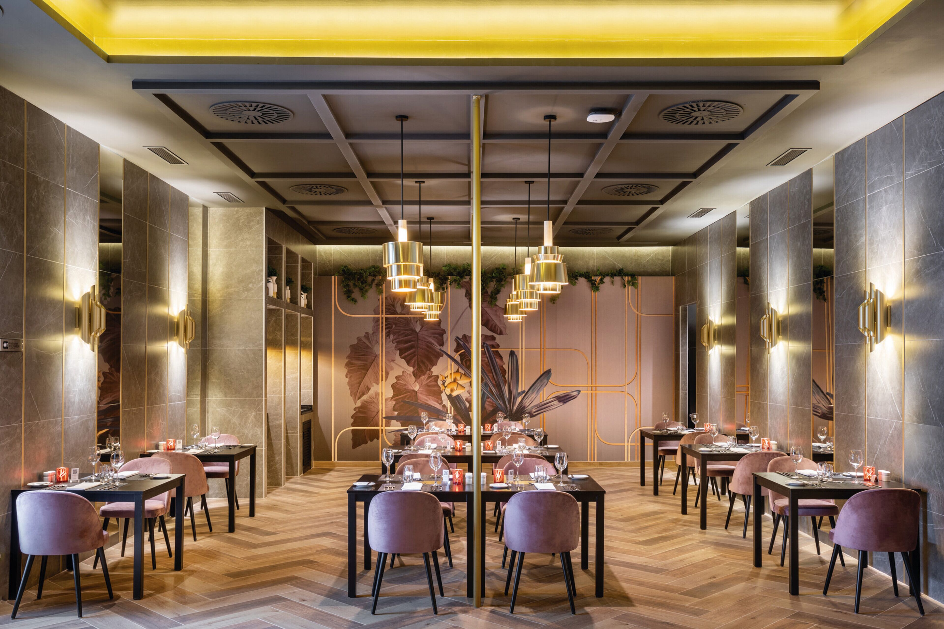 Un restaurante con varias mesas y sillas, un techo decorativo e iluminación en la pared.