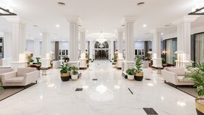 A spacious lobby with a marble floor, white columns, and modern lighting fixtures. - Hotel Riu Madeira - All Inclusive (Santa Cruz)