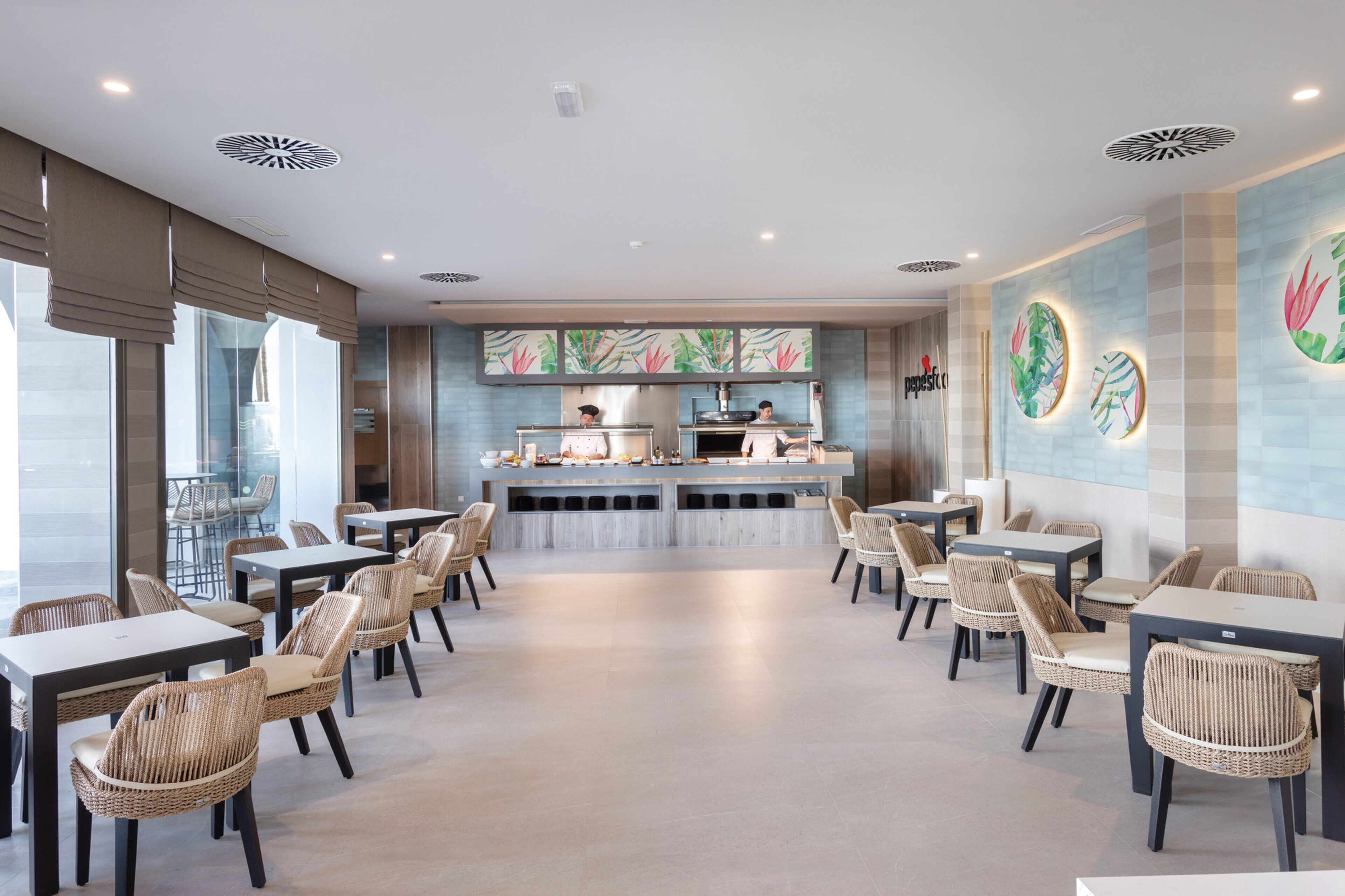 Un restaurant moderne avec un comptoir central, des chaises en osier et une vue sur la rue.