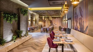 Un espace de restauration moderne, doté de plusieurs tables et chaises, d’un éclairage décoratif et d’un sol orné d’un motif en chevrons.