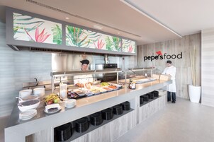 A buffet setup with various food items and a staff member.
