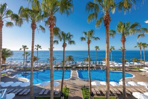 A pool area with multiple swimming pools, palm trees, and lounge chairs.