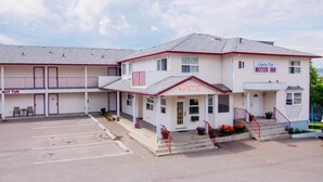 A motel with a two-story structure, a parking lot, and a sign indicating a motor inn.