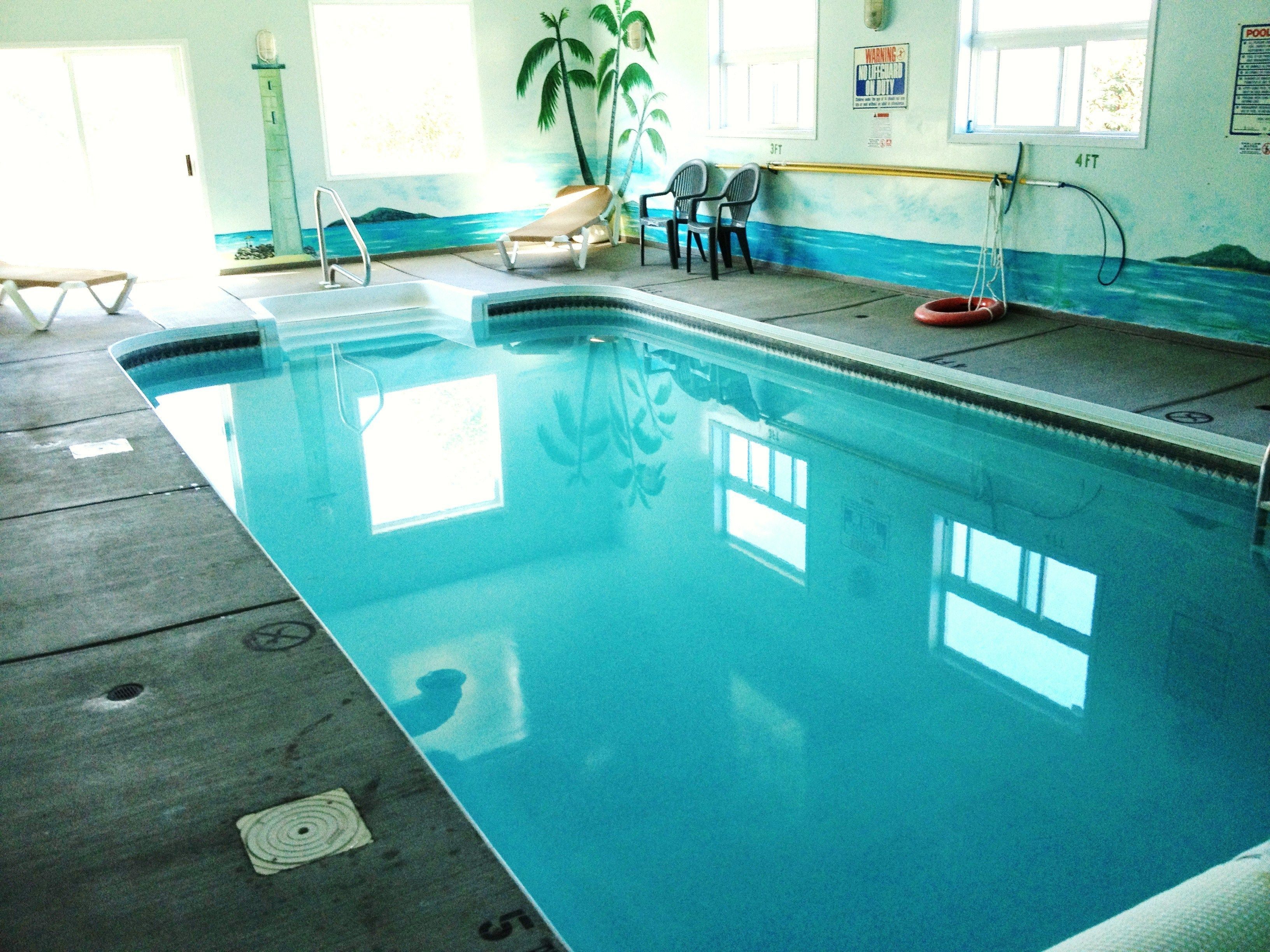 An indoor swimming pool with clear water, a lifeguard chair, and a sun lounger.
