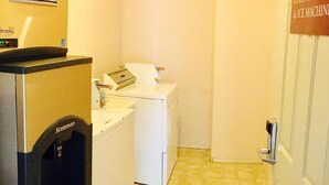 A laundry area with a washing machine, dryer, and a sign indicating guest laundry and ice machine services. - Country View Motor Inn (Kamloops)