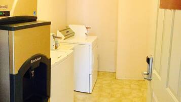 A laundry area with a washing machine, dryer, and a sign indicating guest laundry and ice machine services.