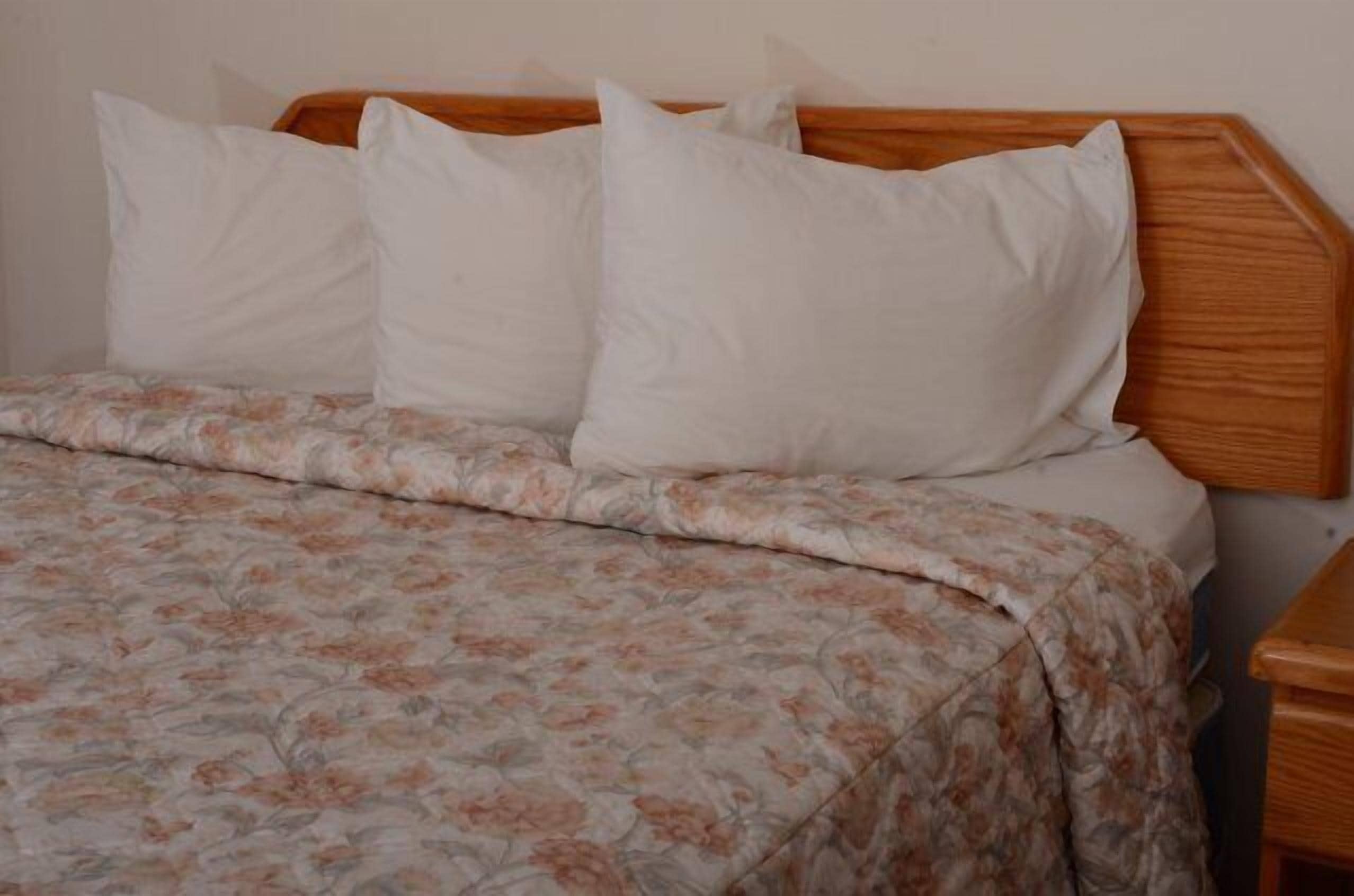 A bed with a floral-patterned bedspread and white pillows.