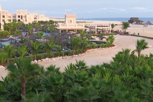 Un resort con zona de piscina, palmeras y acceso a la playa.
