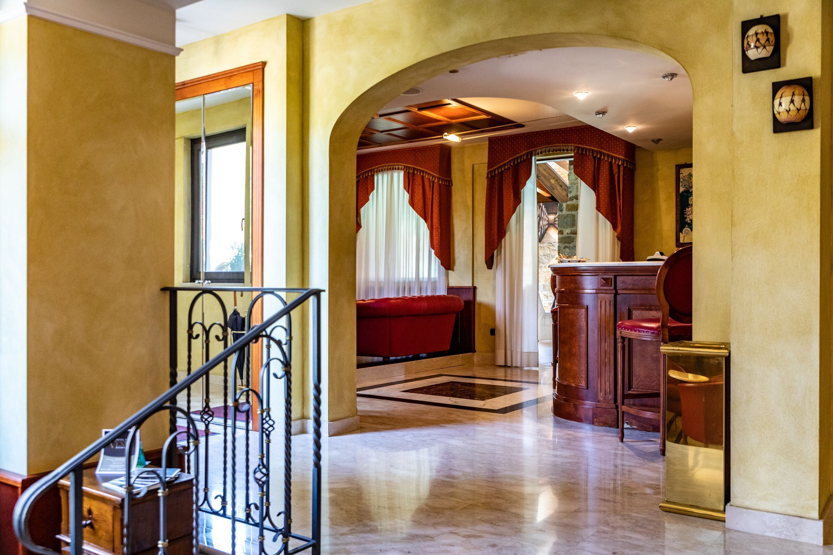 A grand hallway with a marble floor, a red sofa, and a wooden cabinet.