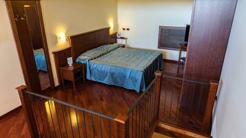 Un dormitorio con una cama de madera, mesitas de noche, un escritorio y una silla.