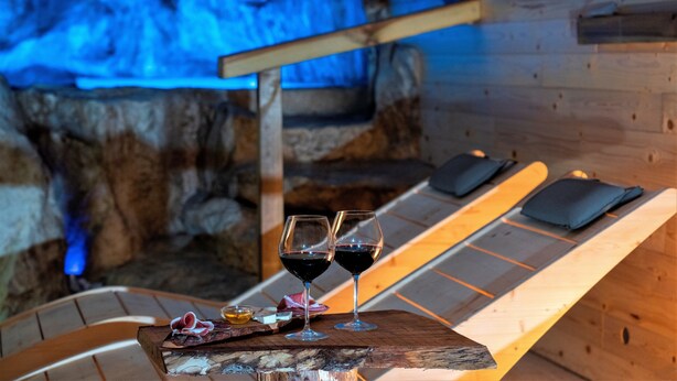A wooden lounge chair with a tray holding two glasses of red wine and a small dish of cheese. - Hotel Villa Venus (Atena Lucana)