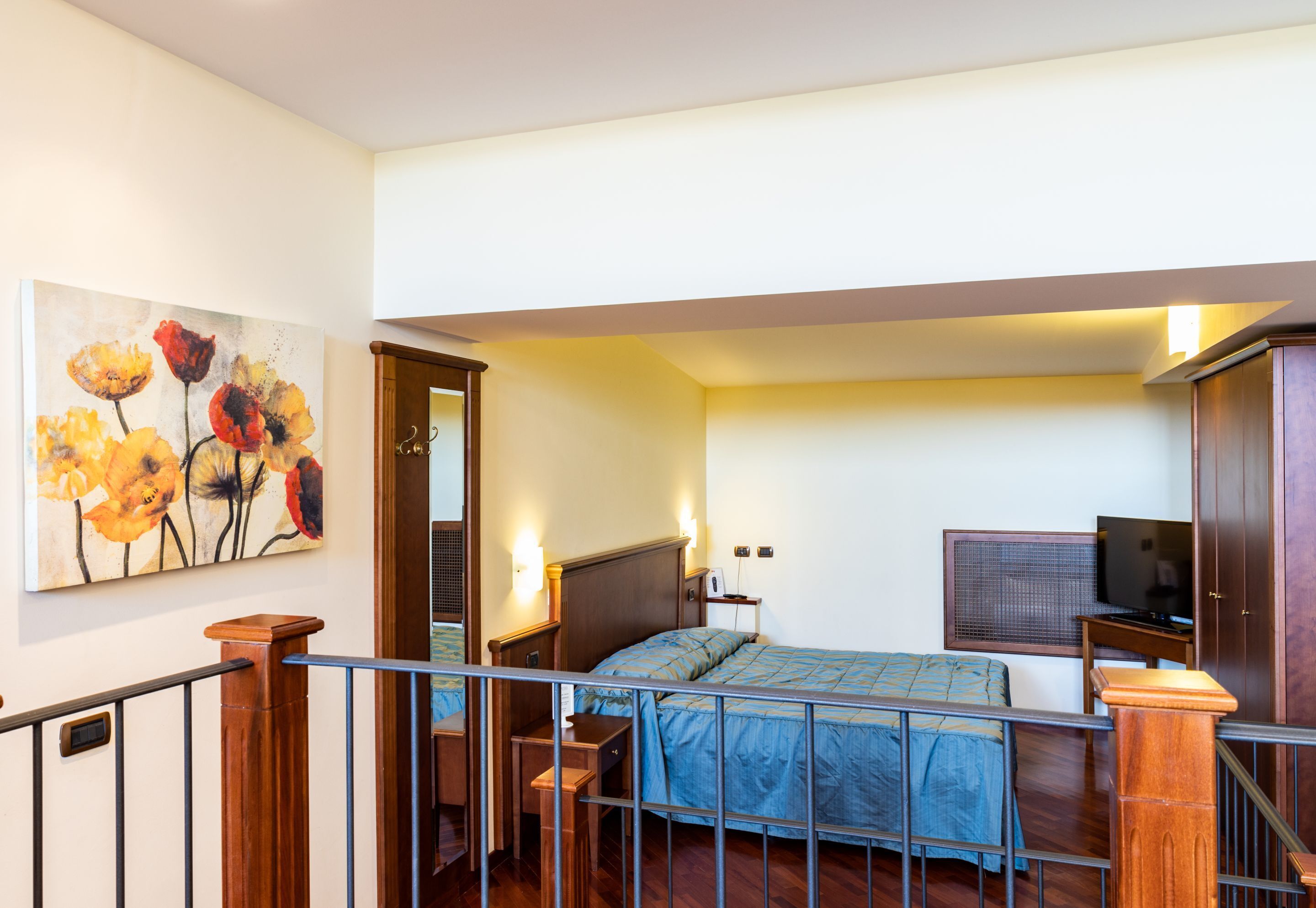 Quarto com cama, televisão e um quadro na parede.