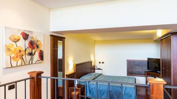 Quarto com cama, televisão e um quadro na parede.