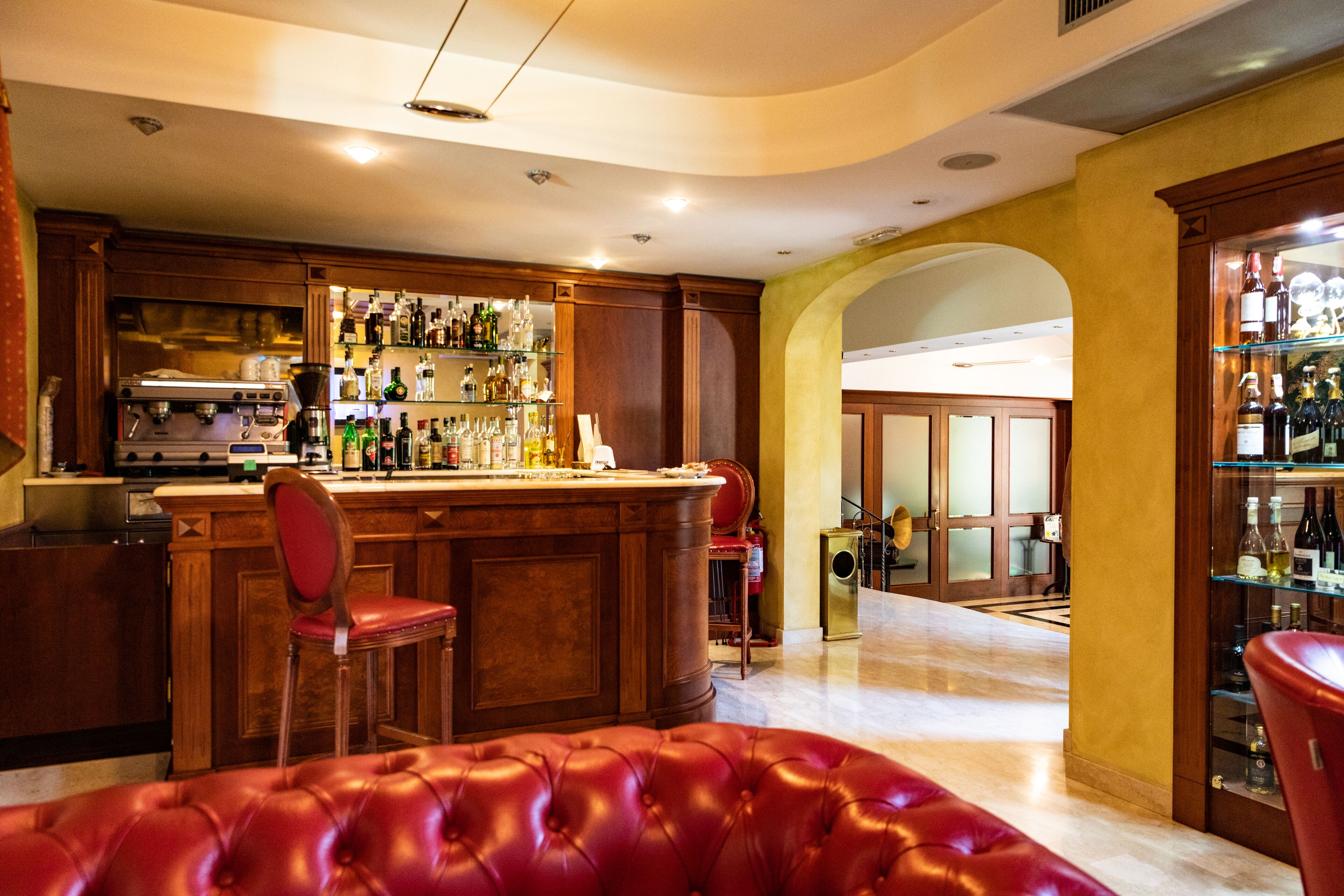 A bar area with a counter, stools, and a red leather couch.