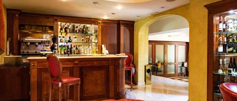 Una zona de bar con mostrador, taburetes y un sofá de cuero rojo.