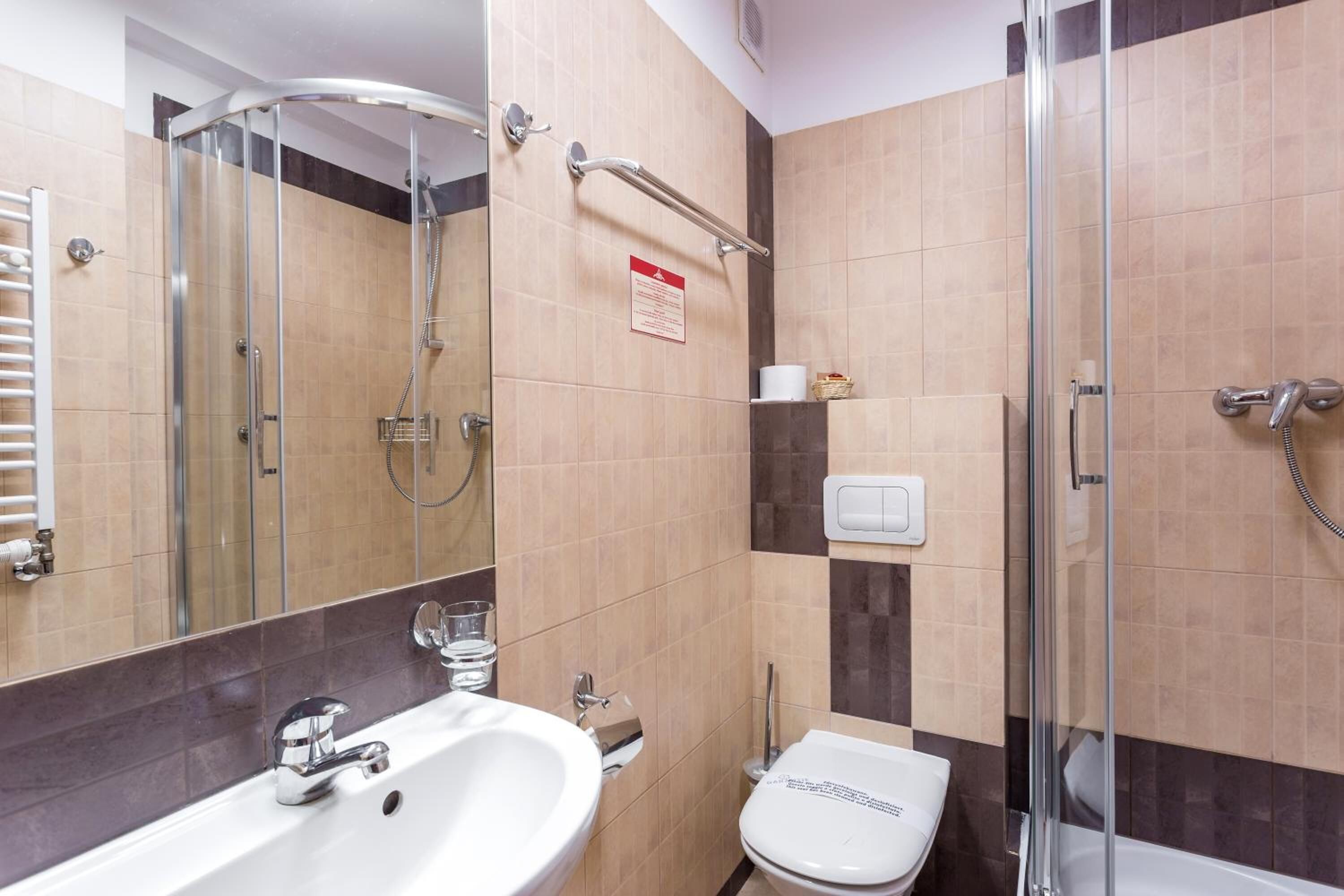 Een moderne badkamer met een douchecabine van glas, een witte wastafel en een toilet.