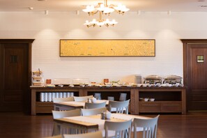 A buffet area with a central serving station, multiple seating arrangements, and a large decorative wall piece above the counter. - Hotel Relaks Wellness & SPA (Karpacz)