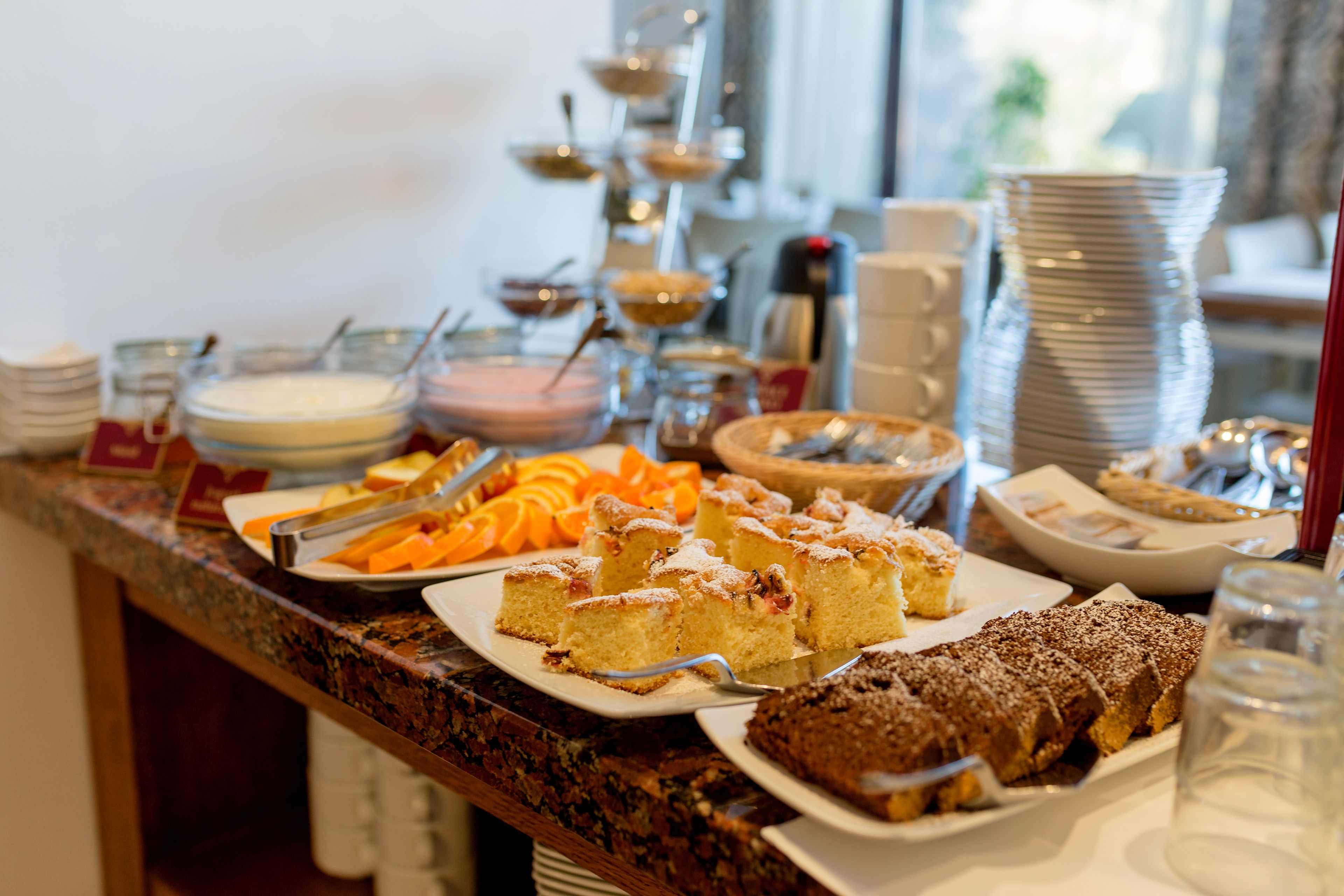 A buffet with various dishes including cakes, fruits, and beverages.