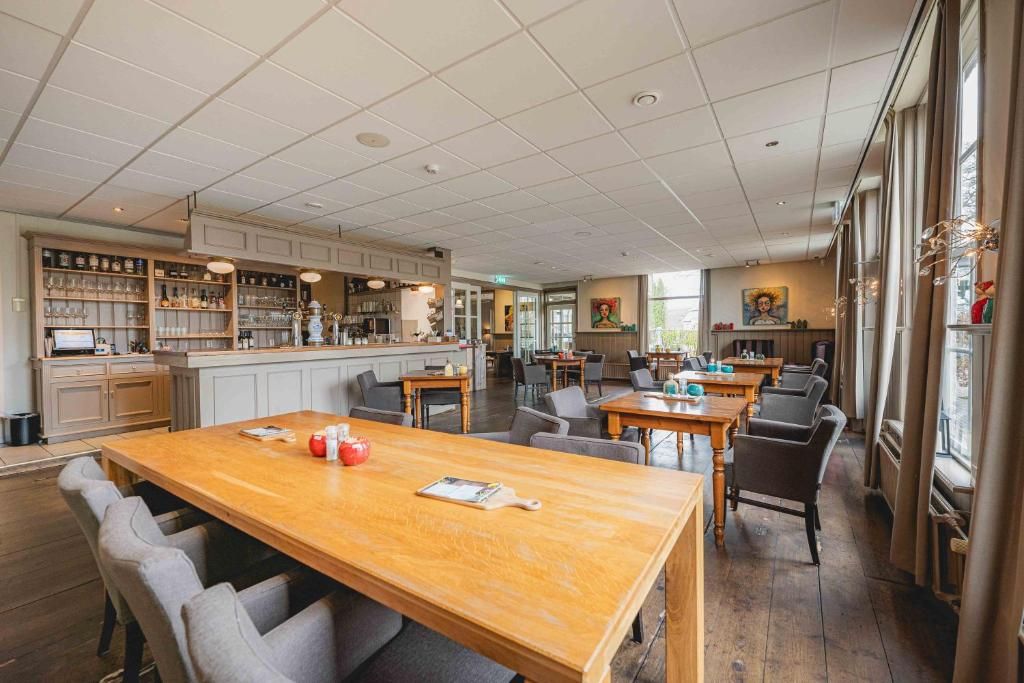 En rymlig restaurang med en bardel, träbord och stolar.