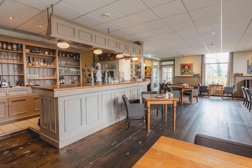 A bar area with a wooden counter, shelves with bottles, glasses, and a seating area with tables and chairs.