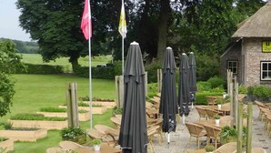 An outdoor seating area with tables and umbrellas at a building named 'Herberg De Klomp'. - De Klomp - Charme Hotel & Restaurant (Vilsteren)