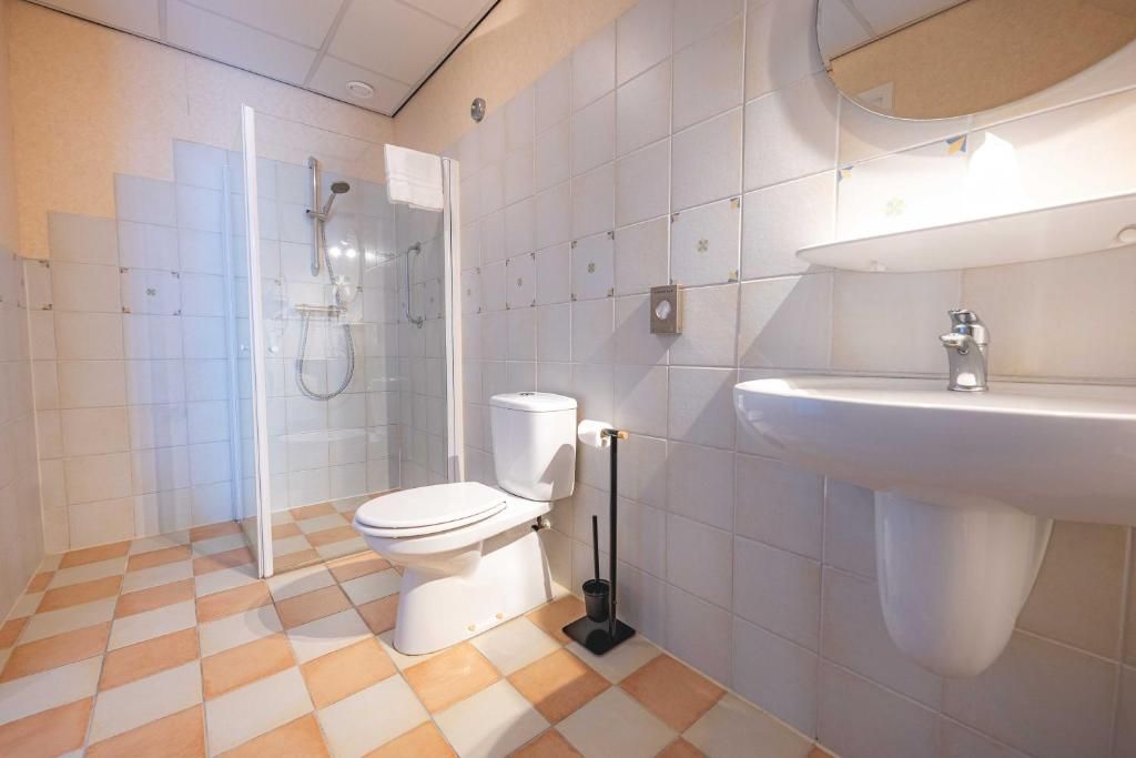 A bathroom with a glass-enclosed shower, a white toilet, and a sink.