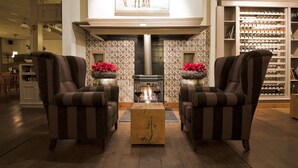 A cozy living room with striped armchairs, a central coffee table, and a fireplace. - De Klomp - Charme Hotel & Restaurant (Vilsteren)
