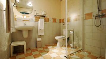 A bathroom with a sink, toilet, and glass shower enclosure.