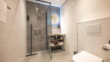 A modern bathroom with a glass-enclosed shower, a white toilet, and a vanity with a mirror.