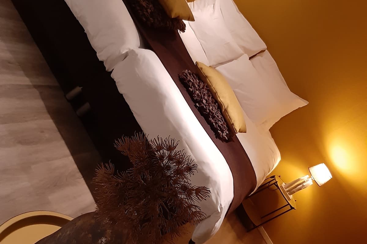 Un lit avec du linge de lit blanc, une tête de lit sombre et deux lampes de chevet.