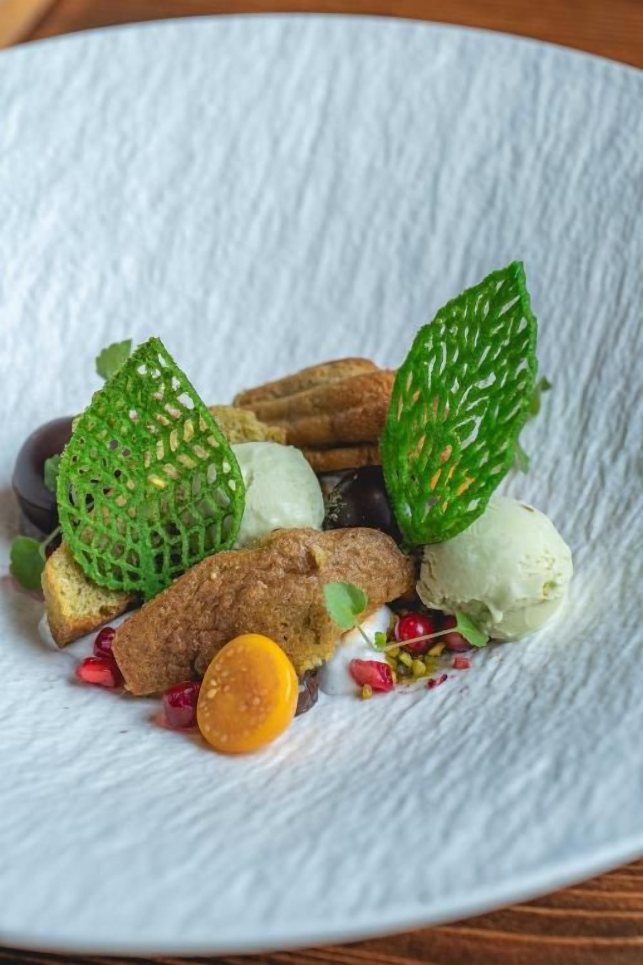 Un plato blanco con textura y comida, incluyendo pan, helado y guarniciones.
