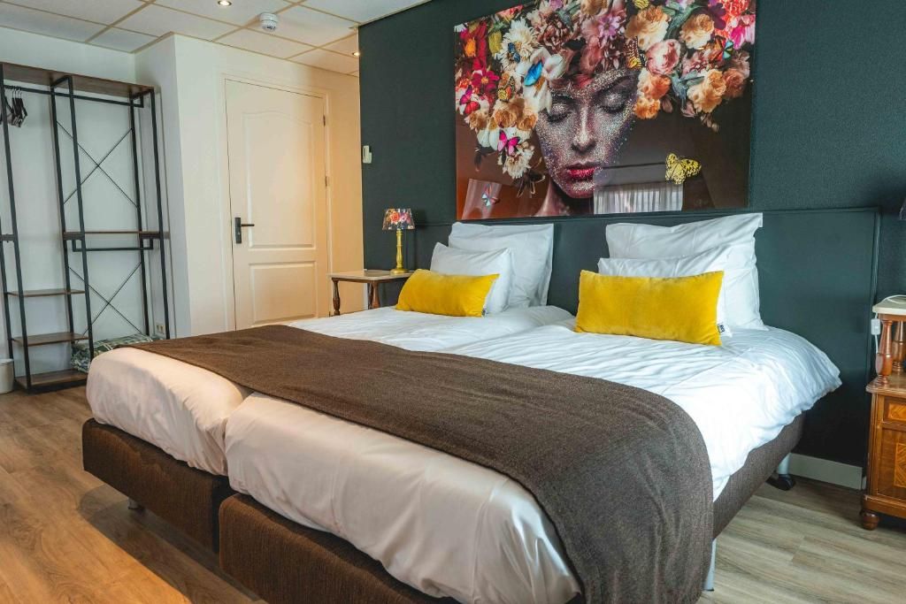 Un dormitorio con cama, almohadas, una obra de arte colgada en la pared, una mesita de noche con lámpara y un armario.