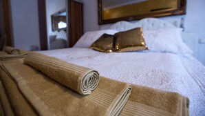 A neatly made bed with rolled towels, a mirror, and decorative pillows. - Hotel Herc (Sarajevo)