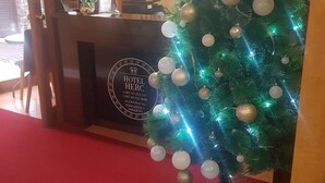 A reception desk with a Christmas tree decorated with ornaments and lights. - Hotel Herc (Sarajevo)