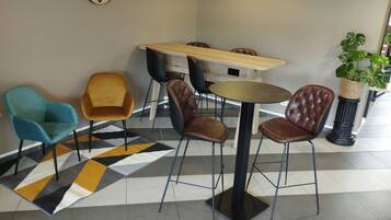 A modern indoor seating area with a round table, four chairs, a clock, and a potted plant.