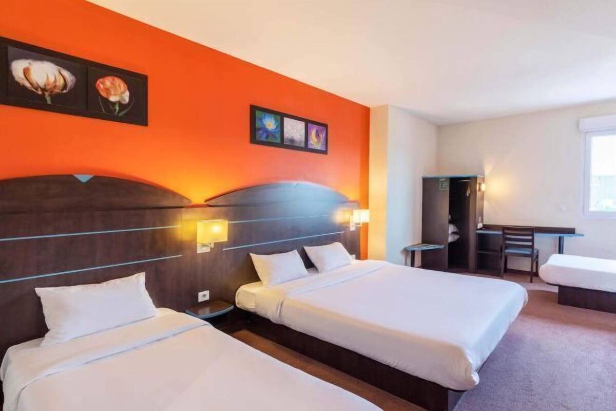 A hotel room with two beds, a desk, and a chair.