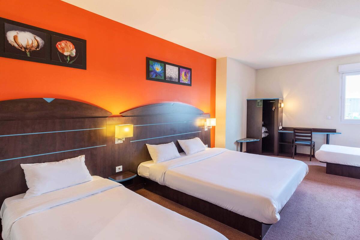 A hotel room with two beds, a desk, and a chair.